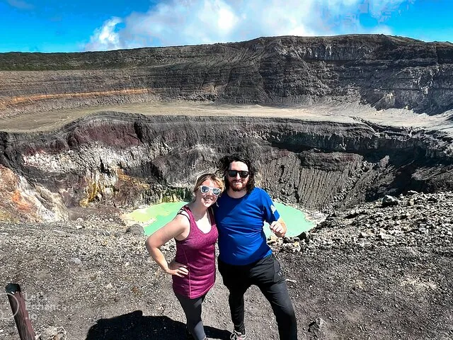A couple posing at the rim of Santa Ana Volcano crater with green lake.