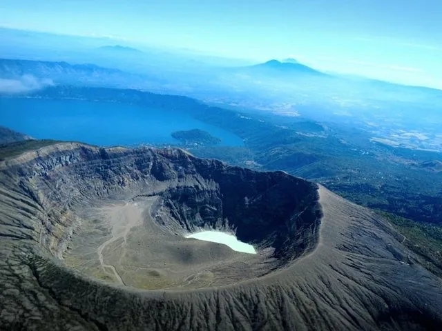 Aerial view of a volcanic crater with a turquoise lake inside.