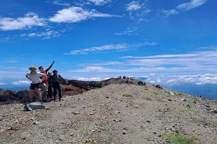 Excursionistas posando en una cresta rocosa con un paisaje volcánico de fondo.